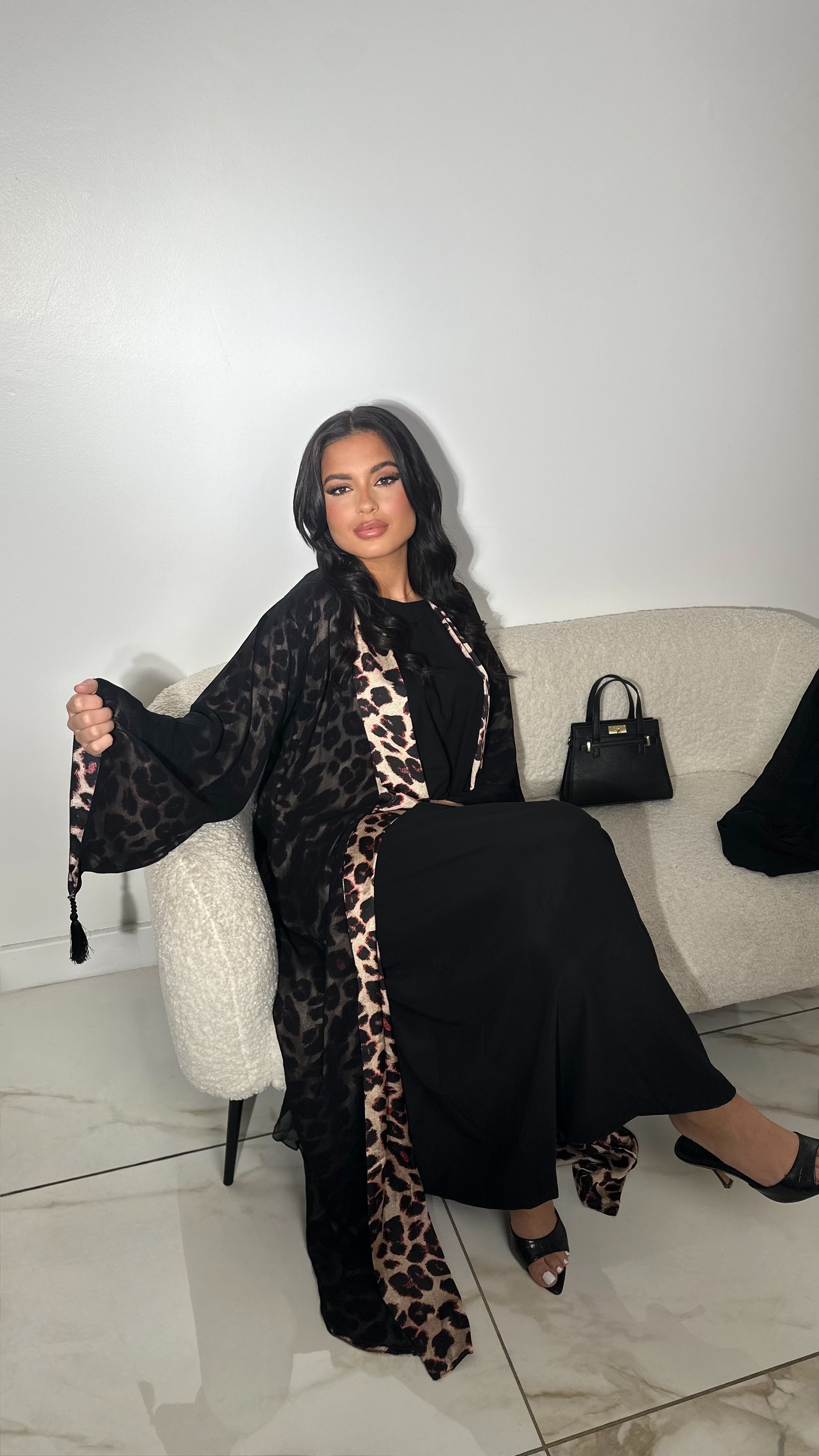 Kimono imprimé léopard aux tons noirs, blanc et beige Détails de plis du kimono avec le motif léopard Voile de tulle léger superposé, laissant deviner les motifs Sous-robe noir satinée incluse Voile assorti intégré Confectionnée à Dubaï Abaya
