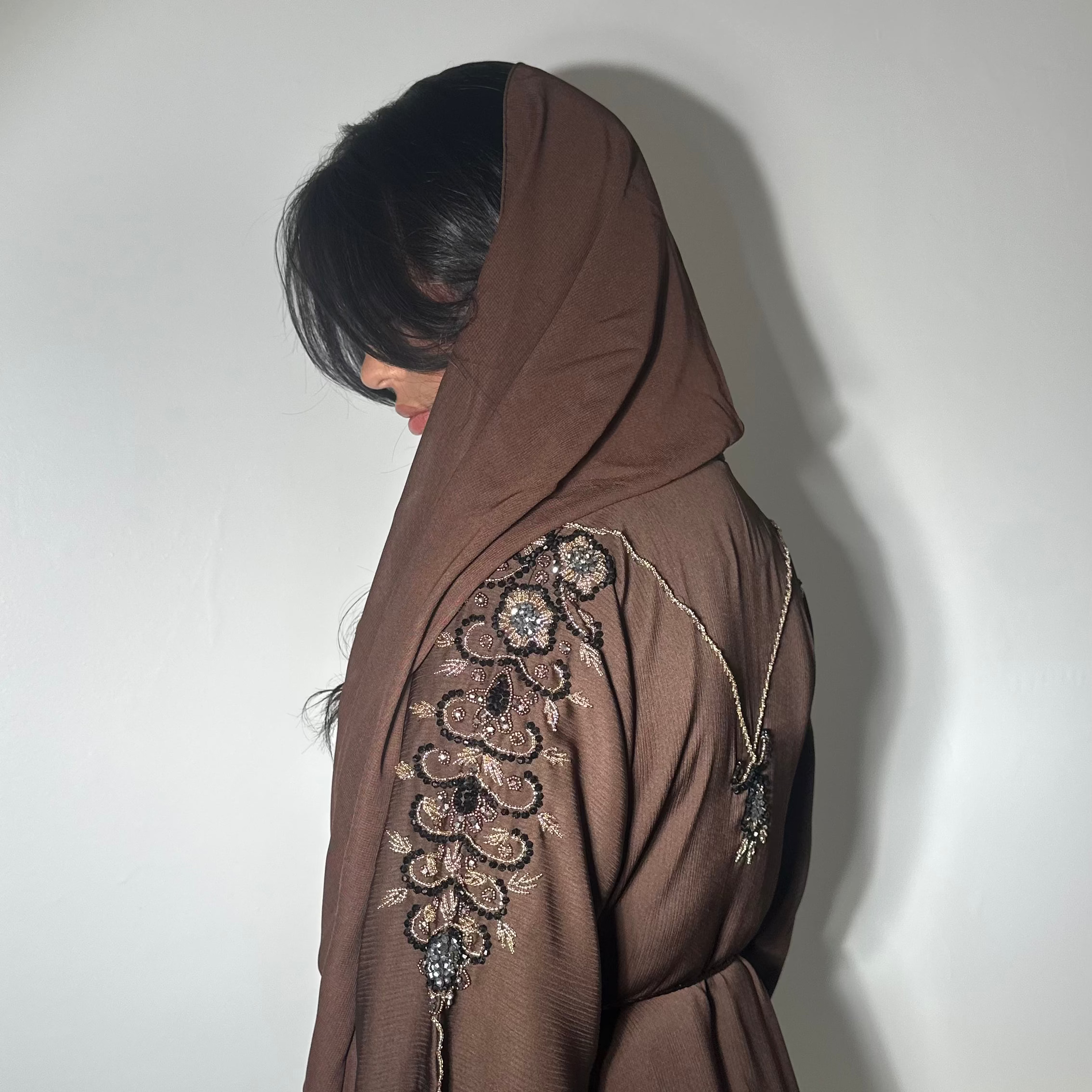Tissu fluide brun
Perlage cousu à la main tout le long des deux manches
Ornement en perles formant un V délicat dans le dos
Voile assorti
Confectionnée à Dubaï