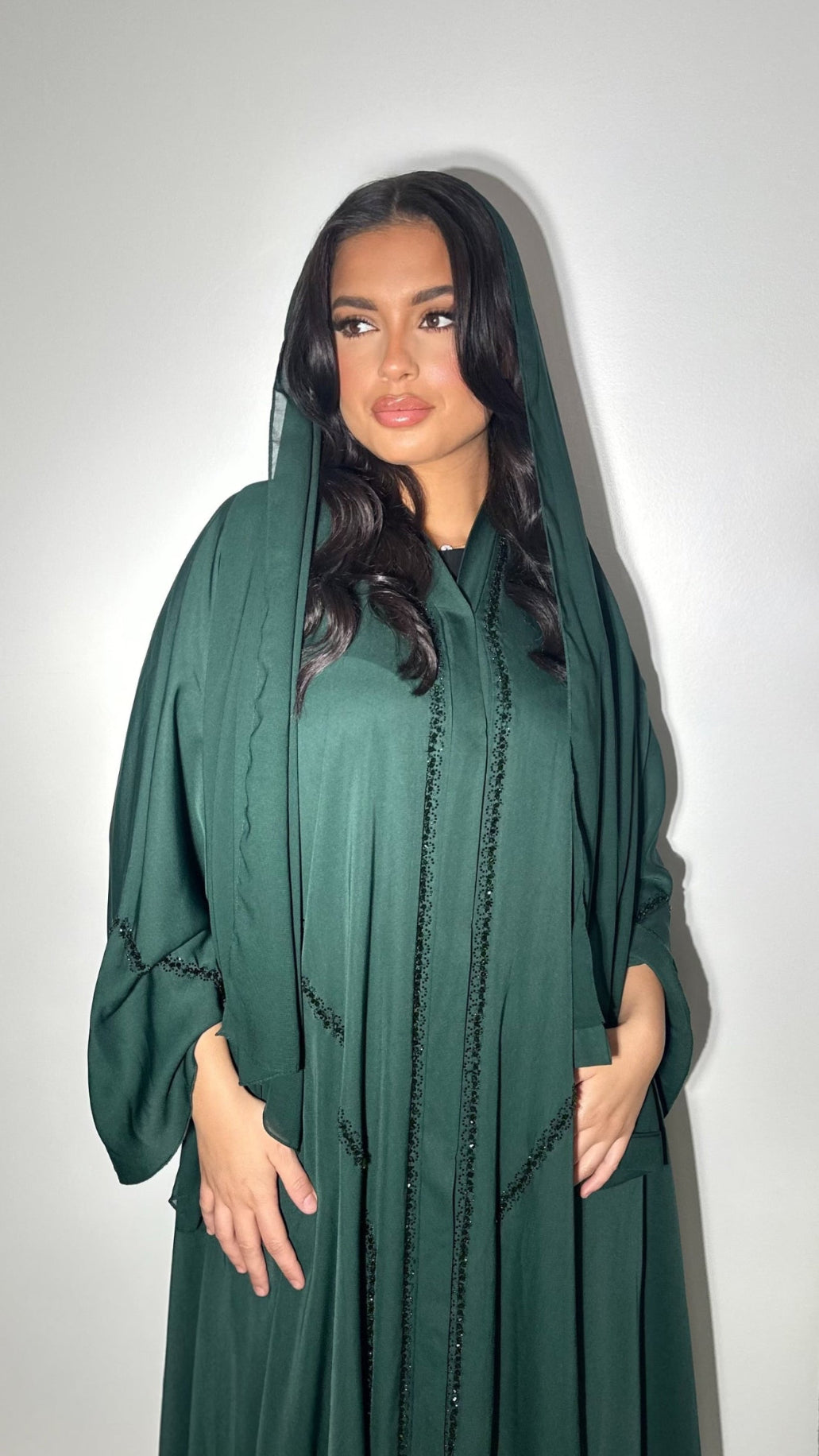 Tissu satin fluide et brillant à la coupe évasée
Manches amples décorées de perles cousues à la main
Voile assorti intégré
Confectionnée à Dubaï Abaya